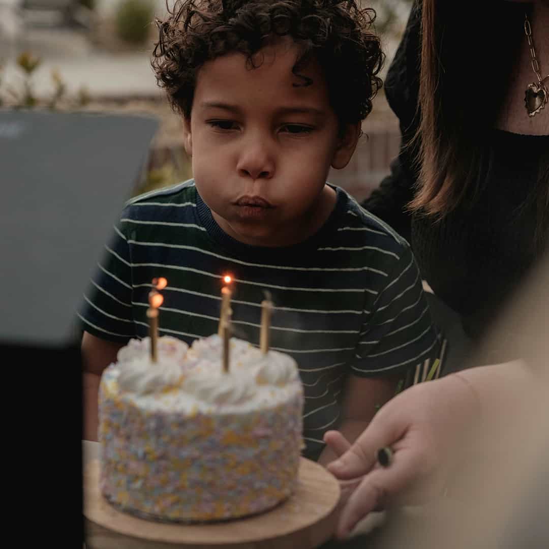 Child blowing out birthday cake candles at a family party